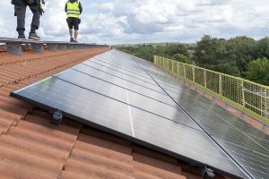 Solceller på taket till kvarteret Kraghandsken. Två montörer går på taket.