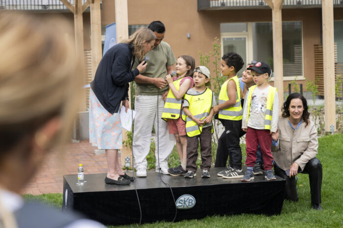 Förskolebarn på en scen utomhus, i samtal med SKBs vd.