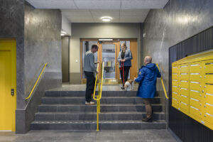 Tre personer samtalar med varandra i ett av trapphusen i SKB-kvarteret Ananasen på Södermalm.