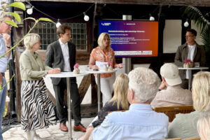 Fem personer i ett scensamtal framför en sittande publik.