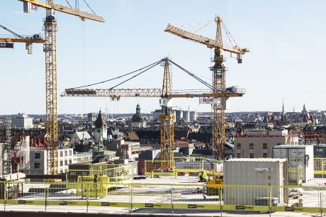 Byggkranar i Hagastaden i förgrunden, centrala Stockholms tak i bakgrunden.