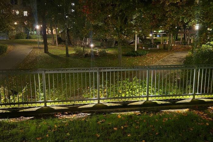 En belyst innergård i mörker, i förgrunden ett staket.