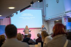 SKBs vd Ingrid Gyllfors och styrelseordförande Charlotte Axelsson står på en scen framför SKBs fullmäktigeledamöter.