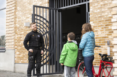 En glad fastighetsskötare håller upp grinden för hyresmedlemmar i kvarteret Torshamn.