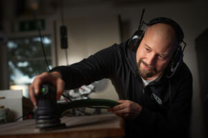 En snickare bearbetar trä i verkstad.